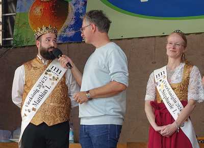 Repräsentierten für ein Jahr den Merziger Viez: Viezkönig Matthias I. (Fox) und Viezkönigin Stéphanie I. (Wagener). In der Mitte: Michael Friemel, Moderator beim Saarländischen Rundfunk. Foto: r3/hb