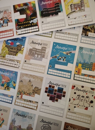 Trierer Altstadtfest-Fans können erneut über die eingereichten Motive abstimmen: Insgesamt 20 Entwürfe stehen in diesem Jahr zur Wahl. Noch bis zum 22. Februar 2026 läuft das Voting. Bildquelle: Trier Tourismus und Marketing GmbH